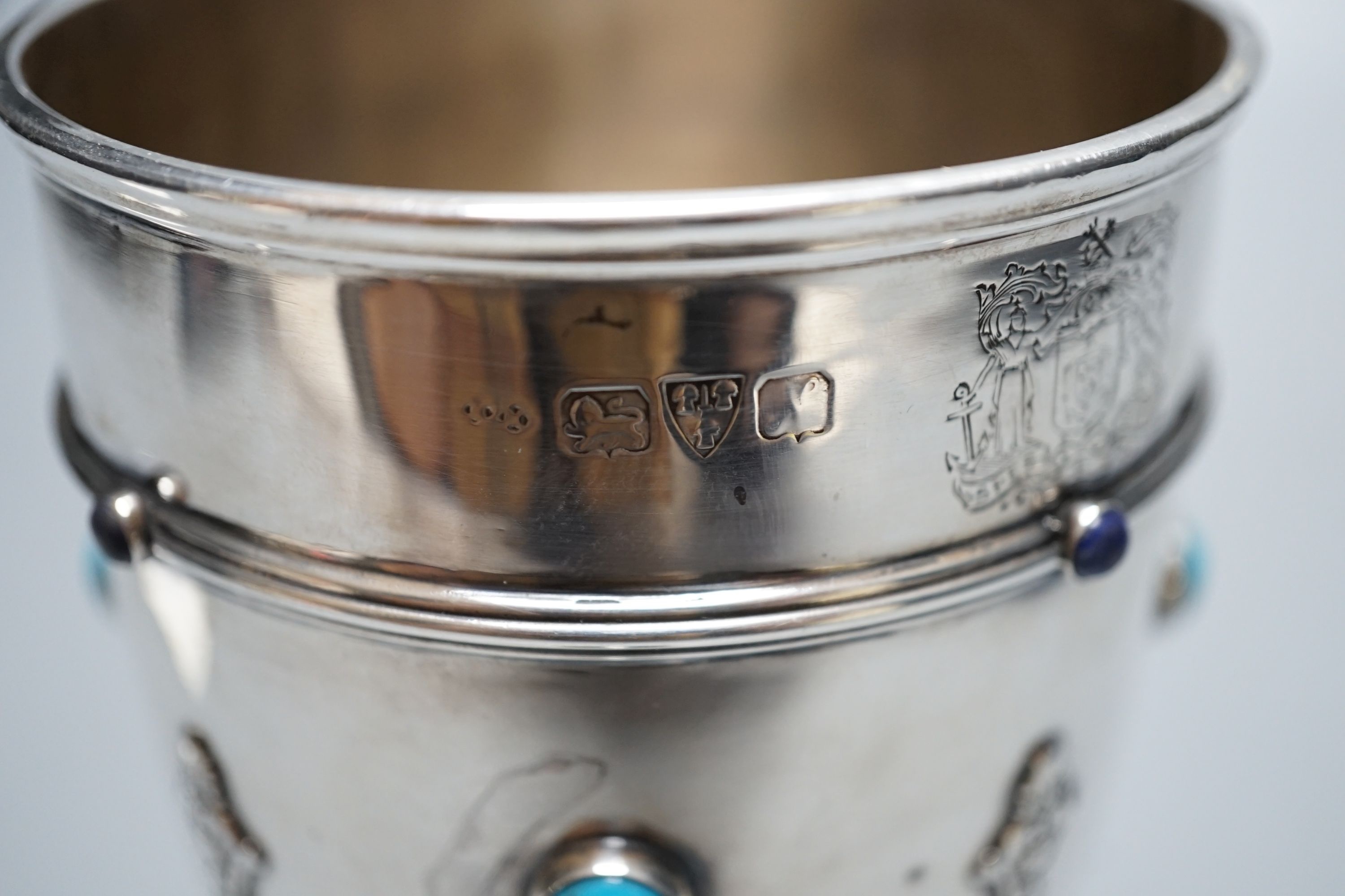 A George V silver goblet or pedestal cup with inset cabochon turquoise and cabochon lapis lazuli, with engraved crest and strapwork decoration, Henry Moreton, Chester, 1913, 13.6cm, gross weight 7oz.
